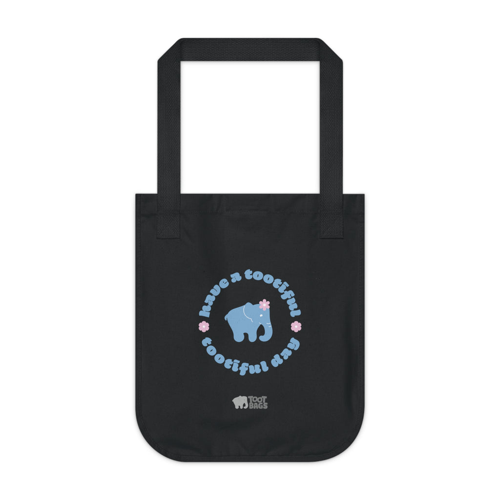 Black canvas tote bag with printed design featuring a blue elephant and 'have a tootiful tootiful day’ text with pink floral design on a a white background.