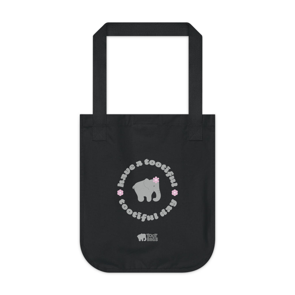 Black canvas tote bag with printed design featuring a gray elephant, gray 'have a tootiful tootiful day’ text with pink floral design on a white background.