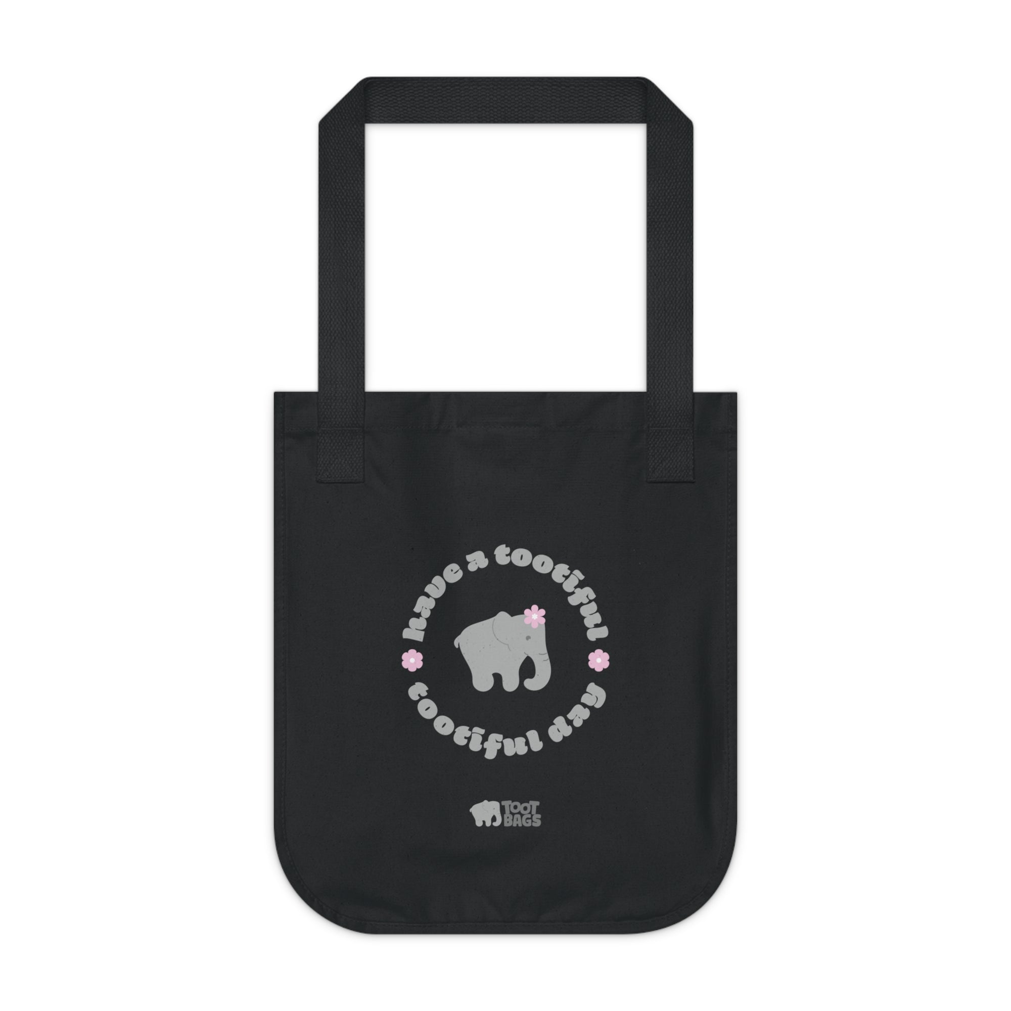 Black canvas tote bag with printed design featuring a gray elephant, gray 'have a tootiful tootiful day’ text with pink floral design on a white background.