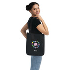 Woman carrying a black canvas tote bag with a printed heart design featuring a pink elephant and colorful flowers on a white background.