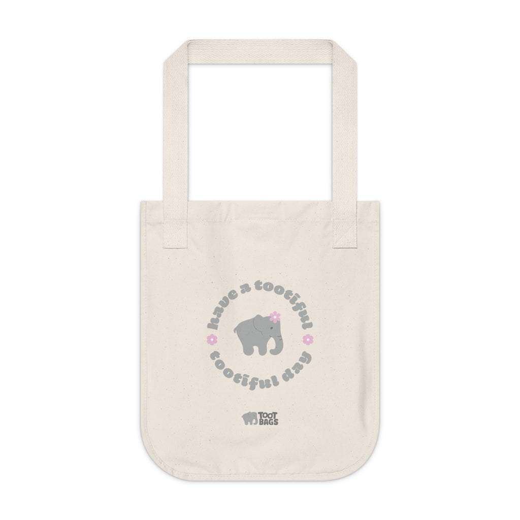 Natural beige canvas tote bag with printed design featuring a gray elephant, gray 'have a tootiful tootiful day’ text with pink floral design on a white background.