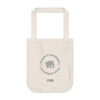 Natural beige canvas tote bag with printed design featuring a gray elephant, gray 'have a tootiful tootiful day’ text with pink floral design on a white background.