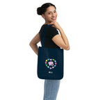 Woman carrying a navy blue canvas tote bag with a printed heart design featuring a pink elephant and colorful flowers on a white background.