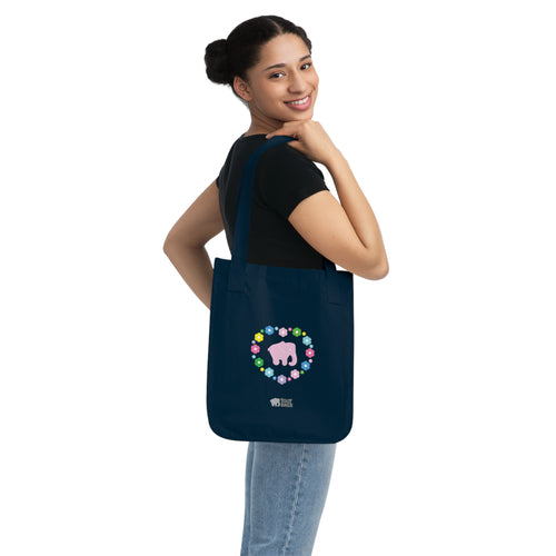 Woman carrying a navy blue canvas tote bag with a printed heart design featuring a pink elephant and colorful flowers on a white background.