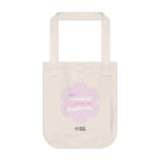 Natural beige canvas tote bag with a printed design featuring a pink flower and ‘the peaceful state of gratitude’ text design placed on a white background.